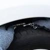 A close-up view of a person wearing a glove installing snow chains on a car tire. Produktbild-Vorschau