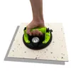 A hand is holding a vacuum lifter with a gauge on a light-colored tile. Produktbild-Vorschau