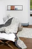 A child's blanket is draped over a daybed in a room with a shelf on the wall. Produktbild-Vorschau