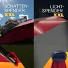 A split image showing a red umbrella. The left side shows the umbrella in daylight with the text "SCHATTEN-SPENDER XXL" and the right side shows the umbrella at night with LED lights and the text "LICHT-SPENDER XXL". A solar panel is visible on the right s Produktbild-Vorschau