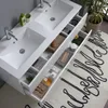 A white double vanity with sinks and open drawers displaying bathroom accessories. Anteprima dell’immagine prodotto