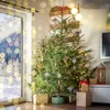 A Christmas tree decorated with ornaments and lights, standing in a room with a window showing a snowy landscape. Podgląd zdjęcia produktu