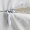 A close-up view of a white zipper on a white fabric. Produktbild-Vorschau