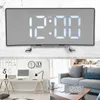A collage of images showing a digital alarm clock, a desk setup with a computer and lamp, and a living room with a sofa and coffee table. The alarm clock is displayed prominently in the top section and on the coffee table in the bottom right section. Produktbild-Vorschau