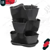 A dark gray vertical planter with three tiers, shown against a blueprint-style background of a house. Produktbild-Vorschau