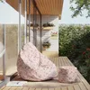 A bean bag chair and ottoman are placed on a wooden deck next to a modern building with large windows and potted plants. Náhled obrázku produktu
