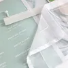 A close-up view of a white sheer curtain with a velcro strip attached to its top edge, laid over a light green surface with text. Produktbild-Vorschau