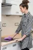 A woman is cleaning a kitchen counter with a purple cloth. Anteprima dell’immagine prodotto