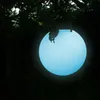 A glowing blue sphere hangs from tree branches in a dark, outdoor setting. Produktbild-Vorschau