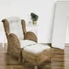 A wicker armchair with a matching ottoman and white cushions, placed on a wooden floor next to a white table with a potted plant. A tall, freestanding mirror is in the background. Produktbild-Vorschau