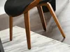 Close-up of the wooden legs and black seat of a chair. Voir les images du produit