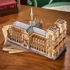 A wooden model of the Notre Dame Cathedral sits on a wooden table, with books in the background. Náhled obrázku produktu