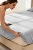 A woman is making a bed with a gray fitted sheet. Podgląd zdjęcia produktu