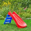 A red and blue plastic slide for children is set up on a green lawn in a garden with various plants and flowers in the background. Anteprima dell’immagine prodotto