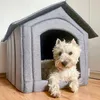 A small white dog is resting in a gray fabric dog house. Produktbild-Vorschau