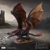 A dragon figurine is displayed on a cracked ground with a castle in the background. Anteprima dell’immagine prodotto