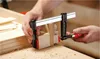 A person is using a clamp to hold two pieces of wood together on a workbench. Anteprima dell’immagine prodotto