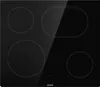 A top-down view of a black induction cooktop with four heating elements. The cooktop has a reflective surface, showing a diagonal glare across the top right. Produktbild-Vorschau