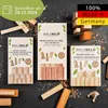 Three boxes of wooden blocks and loose wooden blocks are arranged on a dark, textured surface with wood shavings scattered around. Produktbild-Vorschau
