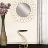A decorative side table with a black top and gold metal frame, placed next to a tall vase with flowers and a round mirror on a wall. Anteprima dell’immagine prodotto