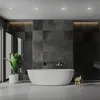 A modern bathroom with a freestanding bathtub, dark tiled walls, and a potted plant. Produktbild-Vorschau