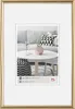 A framed picture of a living room scene with a sofa, coffee table, and decorative items. Produktbild-Vorschau
