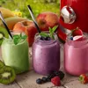 Three mason jars filled with colorful smoothies, surrounded by fresh fruits and a red blender in the background. Produktbild-Vorschau