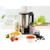 A soup maker is displayed on a white surface with various ingredients and finished products around it, suggesting its use for making soups and smoothies. Produktbild-Vorschau