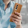 A person holding a brown leather phone case with a Samsung Galaxy Z Fold3 phone inside. Produktbild-Vorschau