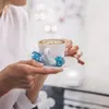 A person holding a cup of coffee with Lindt chocolates. Anteprima dell’immagine prodotto