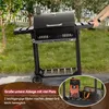 A black Royal Gourmet charcoal grill is shown outdoors on a paved surface with grass and trees in the background. Text overlays describe features. Produktbild-Vorschau