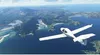 A small white airplane flies over a scenic coastline with islands and water. Náhľad obrázku produktu