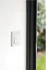 A white light switch with two buttons is mounted on a white wall next to a black door frame. Anteprima dell’immagine prodotto
