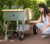 A woman is tending to a raised garden bed on wheels. Produktbild-Vorschau