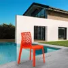 An orange chair is placed on a patio next to a swimming pool, with a modern house in the background. Produktbild-Vorschau