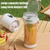 A portable juicer and its container are placed on a wooden table outdoors, with grass and chairs in the background. Produktbild-Vorschau