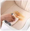A hand is wiping a stain off a beige chair seat with a cloth. Produktbild-Vorschau