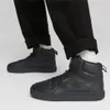 A person wearing black Puma sneakers and black pants. Voir les images du produit