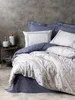 A neatly made bed with a floral patterned duvet cover and blue pillows against a textured gray wall. Produktbild-Vorschau
