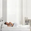A woman is lying on a bed with a mattress topper and a pillow. Produktbild-Vorschau