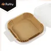 A stack of square paper liners for an air fryer, placed inside a clear plastic container. Náhled obrázku produktu