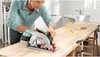 A man is using a Bosch circular saw to cut a wooden countertop in a workshop. Podgląd zdjęcia produktu
