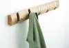 A wooden coat rack with five hooks mounted on a white wall, with a green cloth hanging from one of the hooks. Podgląd zdjęcia produktu