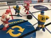 A close-up shot of a table hockey game with four player figurines on the ice. Náhľad obrázku produktu