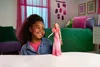 A young girl is holding a Barbie doll in a bedroom setting. Voir les images du produit