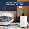 A bedroom scene with a bed, a portable air conditioner, and decorative elements. Produktbild-Vorschau
