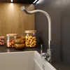 A modern kitchen sink area with a beige faucet, wooden cabinets, and jars of nuts. Anteprima dell’immagine prodotto