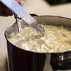 A close-up shot of a person using a knife to cut curds in a pot. Podgląd zdjęcia produktu