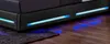 A close-up view of the base of a black LED bed frame with blue lights illuminating the floor and a dark rug. Produktbild-Vorschau