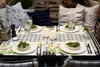 A set table for an outdoor meal, with food, drinks, and decorative elements. Produktbild-Vorschau